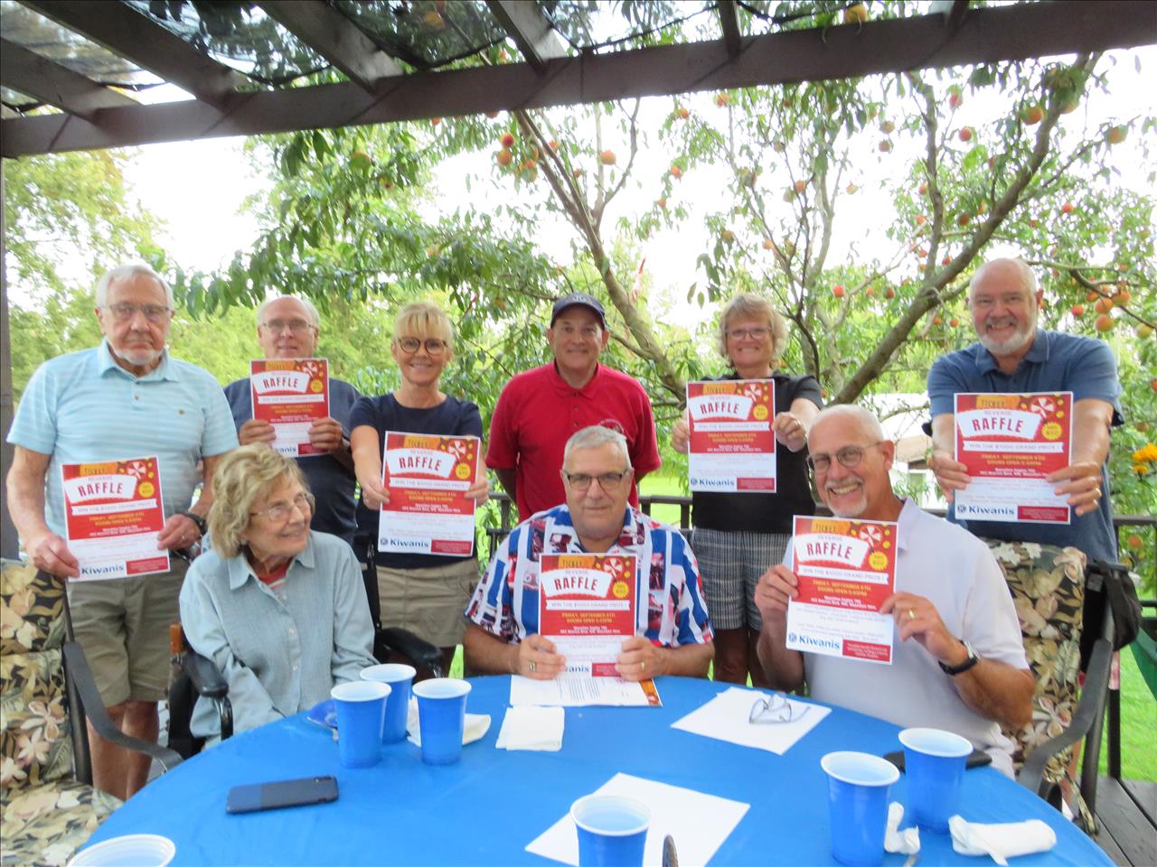 Kiwanis members pose with their marketing flyer for the Reverse Raffle event.