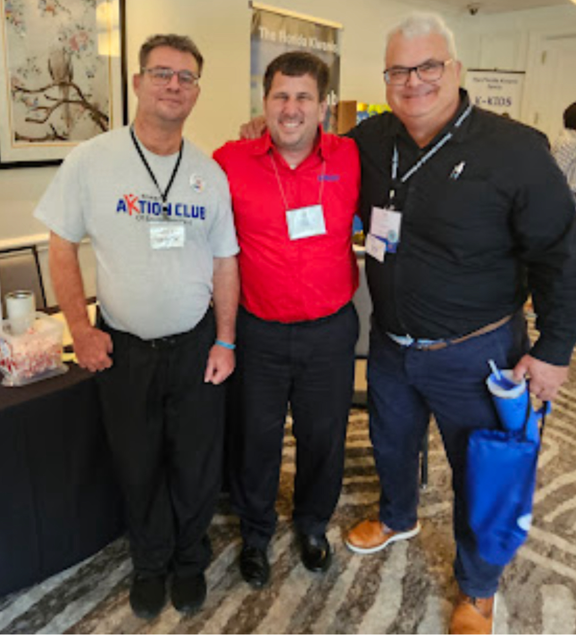 Three Kiwanis family members, including a member of the Aktion Club for adults with disabilities, smiling at a district convention.