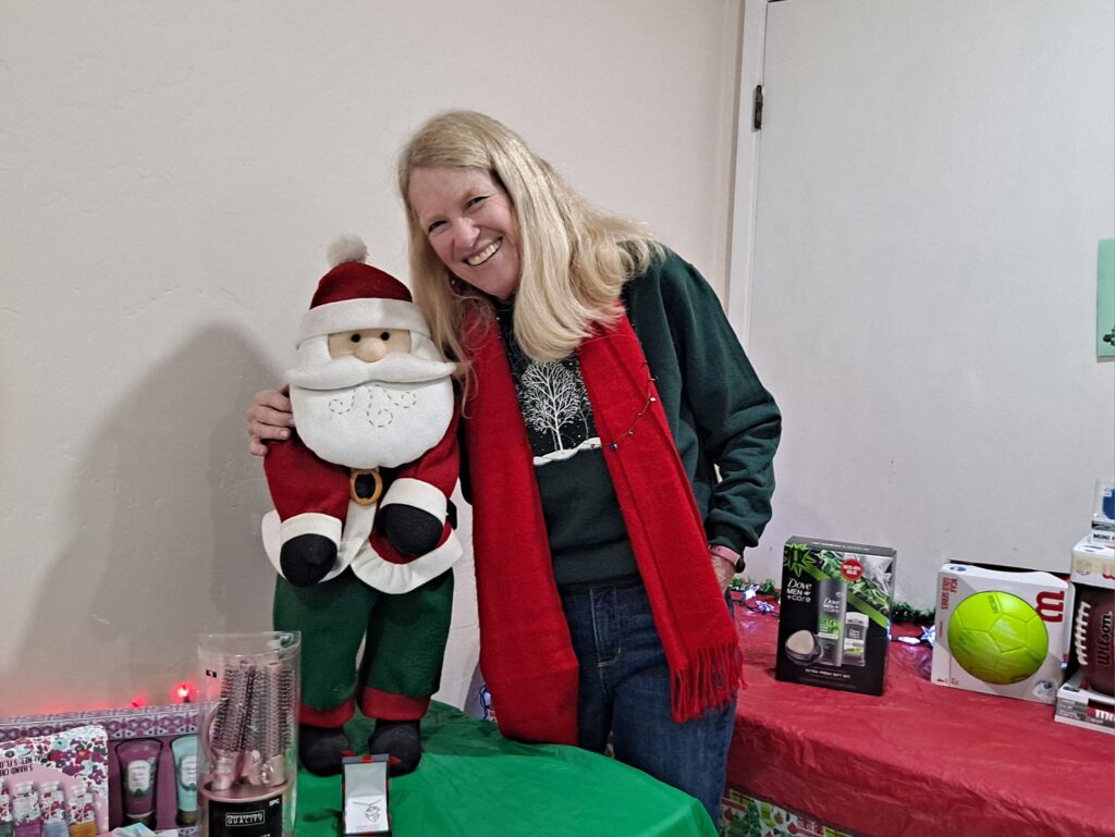 Sue Winters at Toys for Joy, hugging a stuffed Santa, Dec 2023