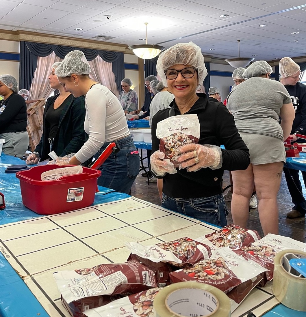 Club member, Elaine, shows off one of the packaged meals of rice and beans that feeds a family of 6