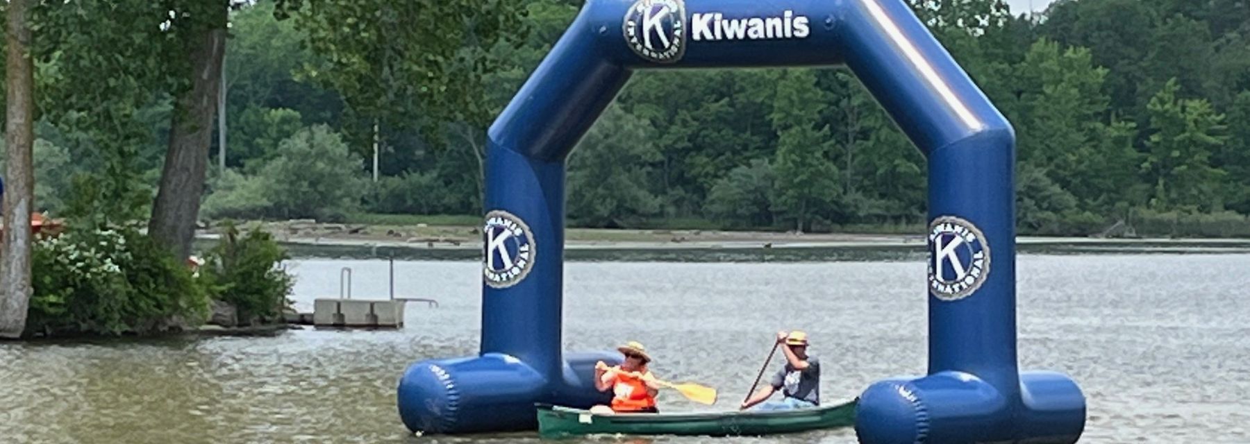 A couple paddles their canoe under the Kiwanis arch finish line