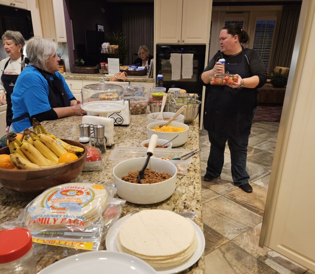 This heartwarming photo captures a moment of community and service inside a kitchen at the Fisher House, where volunteers are preparing a dinner for veterans visiting the VA Hospital.