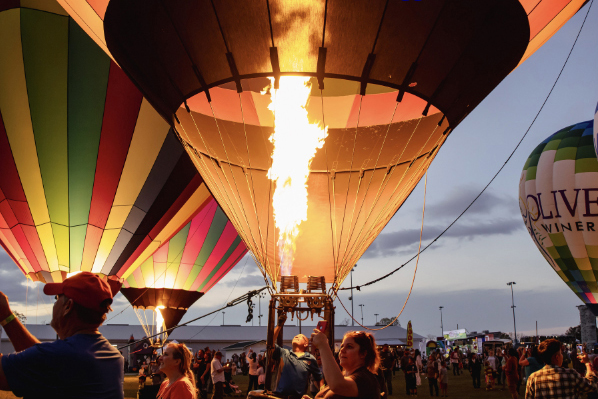 Colorful hot air balloons glowing at dusk during the Kiwanis Indiana Balloon Fest.