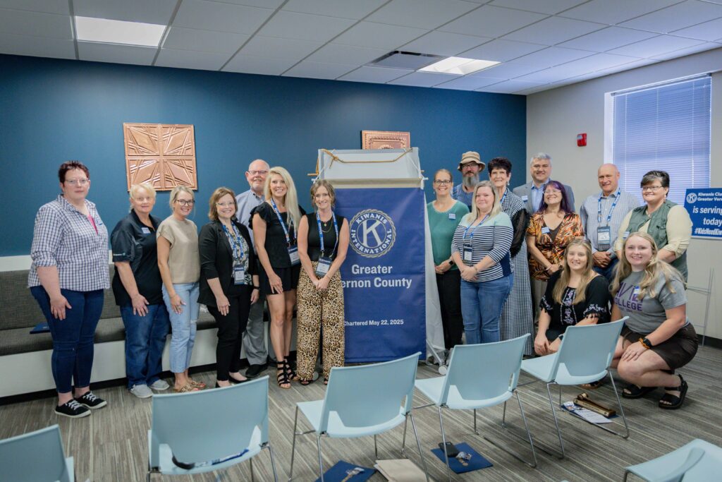 Kiwanis members stand to each side of new club banner.