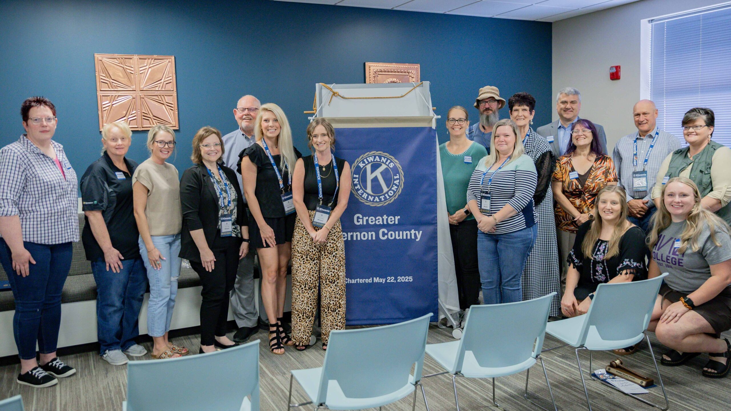 Kiwanis members stand to each side of new club banner.