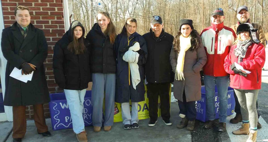 Kiwanis and Key Club members in winter coats outside on a sunny day at a food drive in January, 2024.