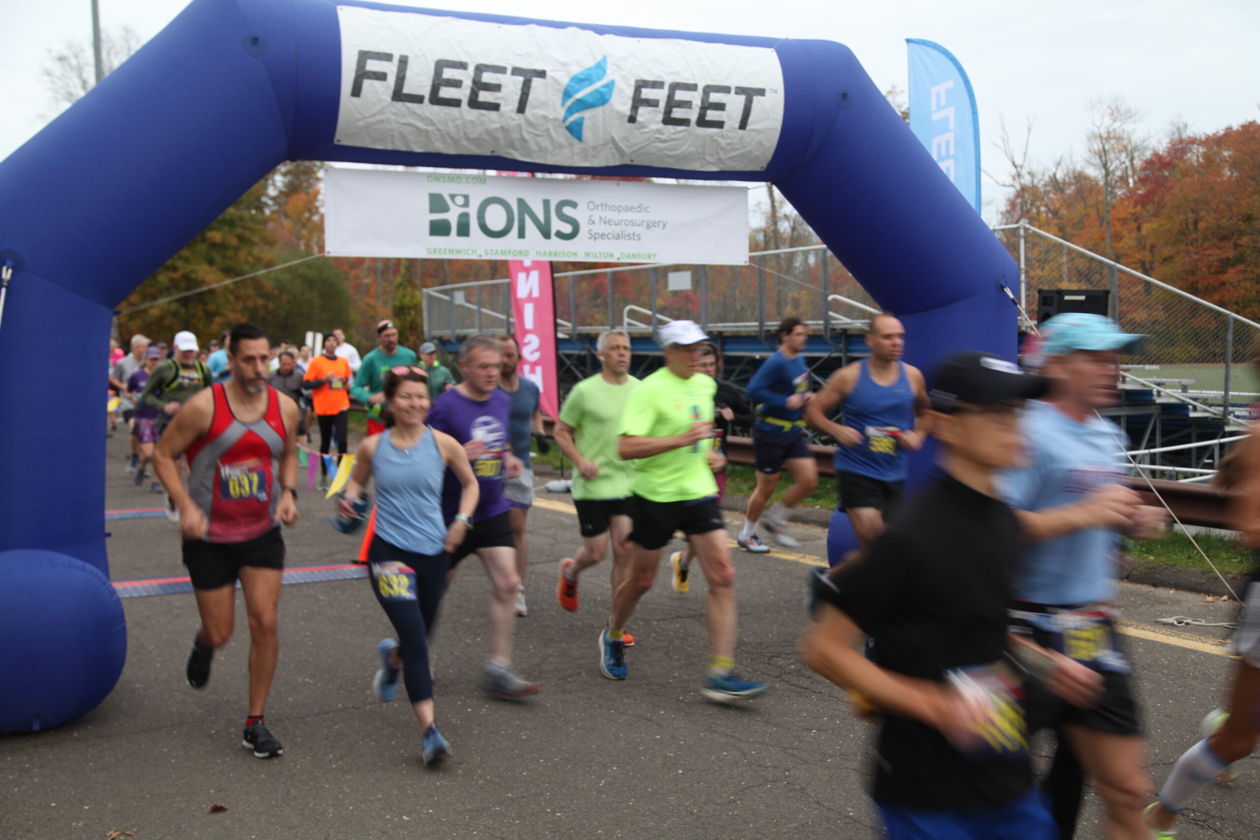 Runners at the start of the half marathon passing under the finish line marker.