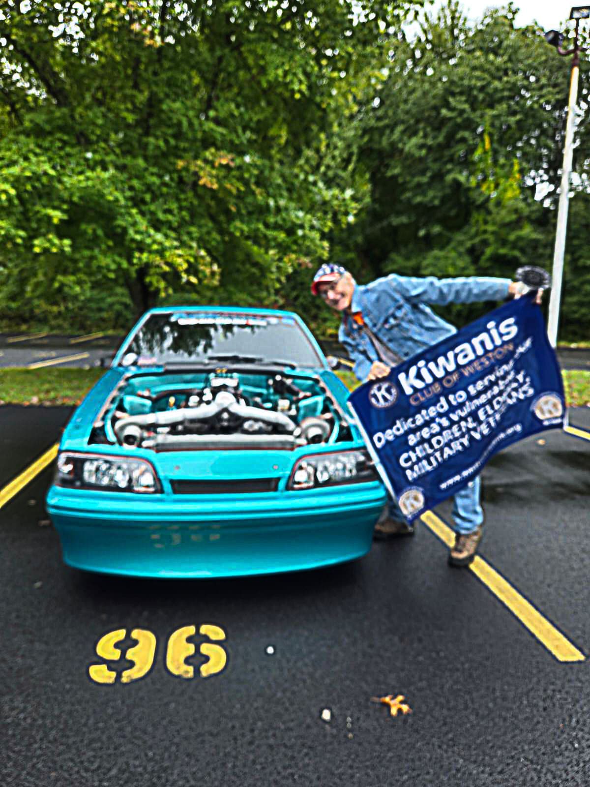 Reed Ameden with Kiwanis banner and an entry at the 2024 inaugural Weston Car Classic.