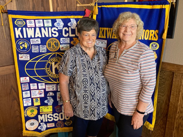 2 Women stand in from of the club flags