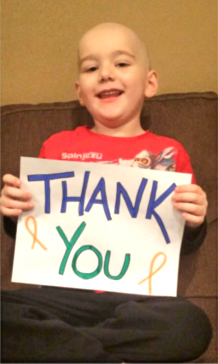 Young boy with cancer showing sign that says thank you