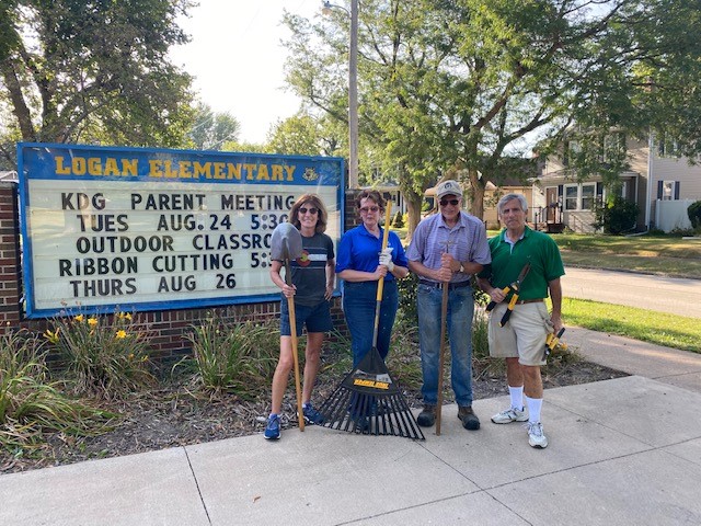 4 people standing in front of a school sign