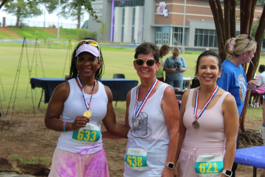 Three 5K finishers wearing medals pose together