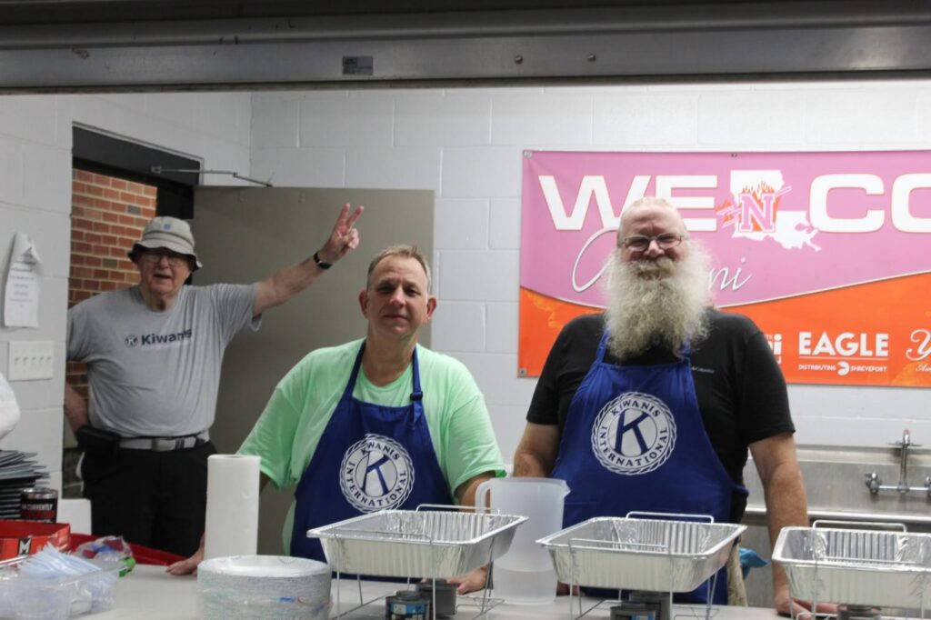 Kiwanis volunteers in aprons serving food in the kitchen