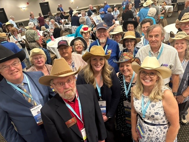 Convention Fun with a large group of people wearing cowboy hats and smiling at the camera.