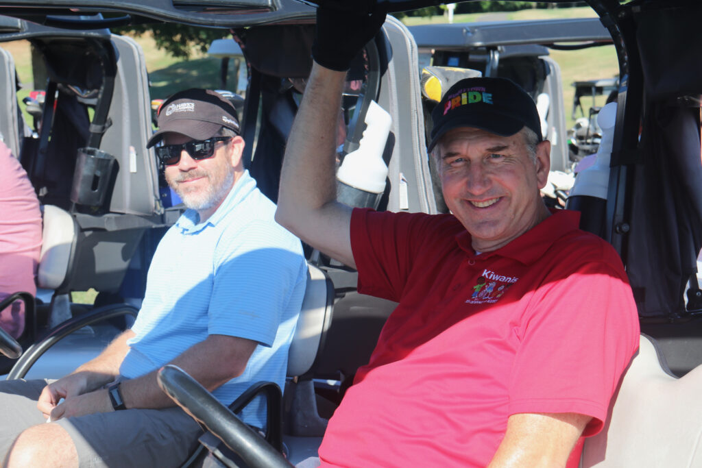 Two golfers posing for a photo in the golf cart.