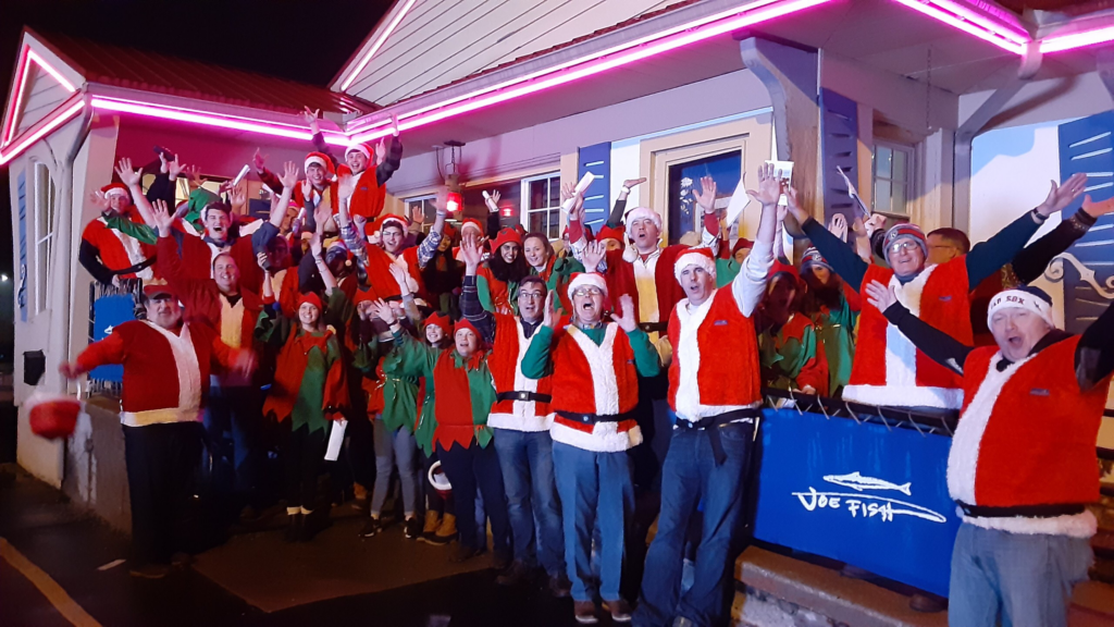 The Santa Night Singers on their 2019 Caroling Tour. Shown here in front of Joe Fish in North Andover. Just one of 15 stops where they entertained the patrons and passed Santa's sack collecting donations to support the children of the Merrimack Valley.